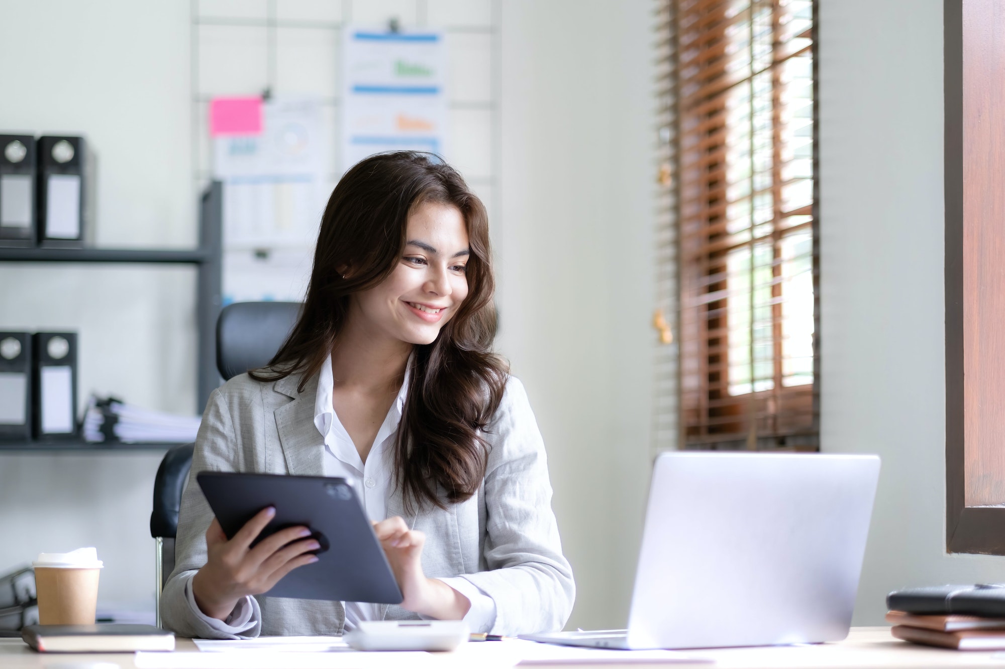 Asian Business woman using calculator and laptop for doing math finance on an office desk, tax